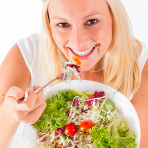 Junge Frau isst frischen bunten Salat